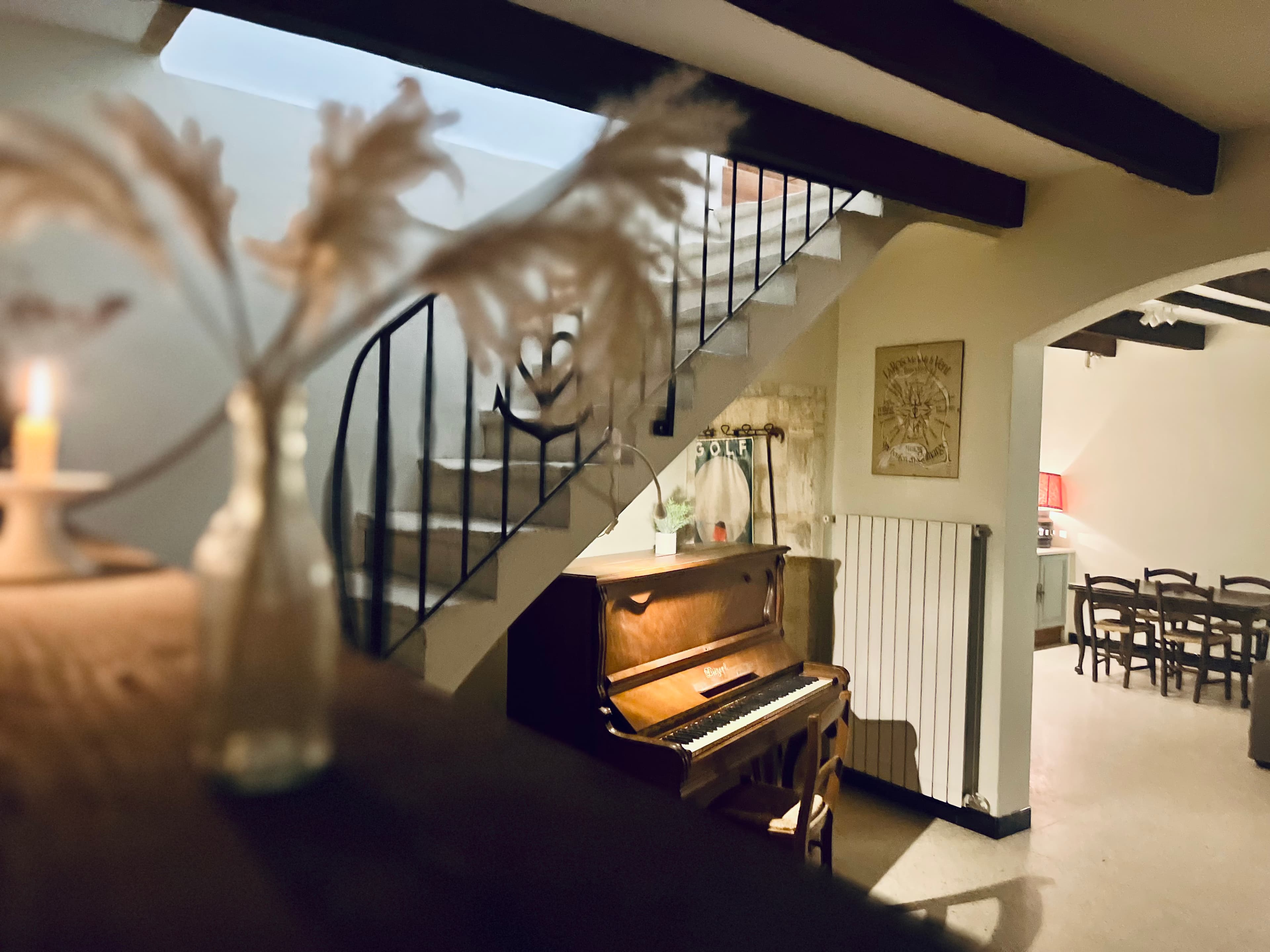 Entrance hall with vintage upright piano beneath a wrought-iron staircase
