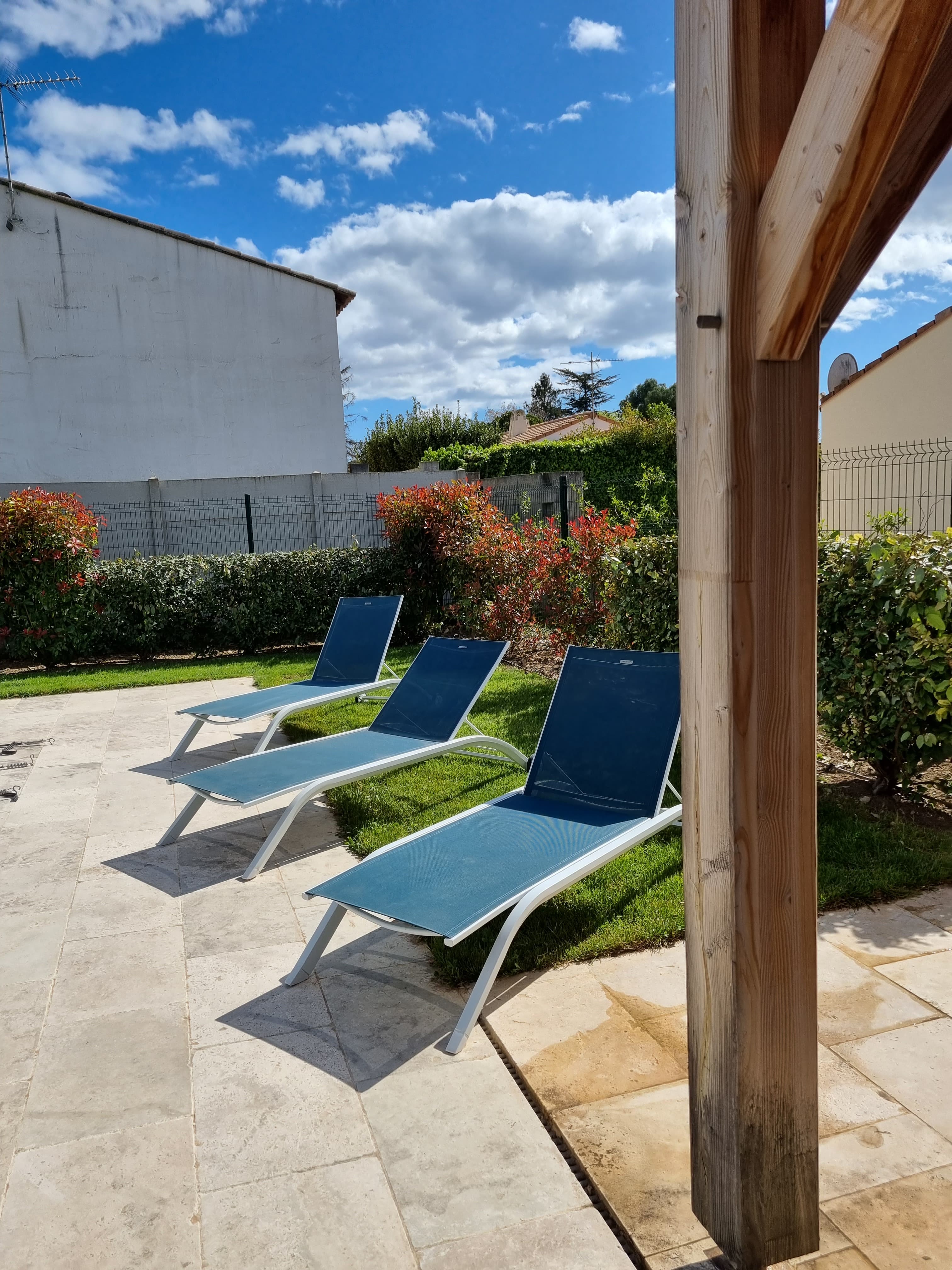Three blue sun loungers on the limestone terrace beside the pool house